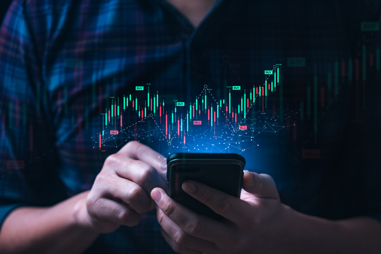 Man holding mobile phone with 3d candle stick trading chart with buy and sell signals | AfterPullback